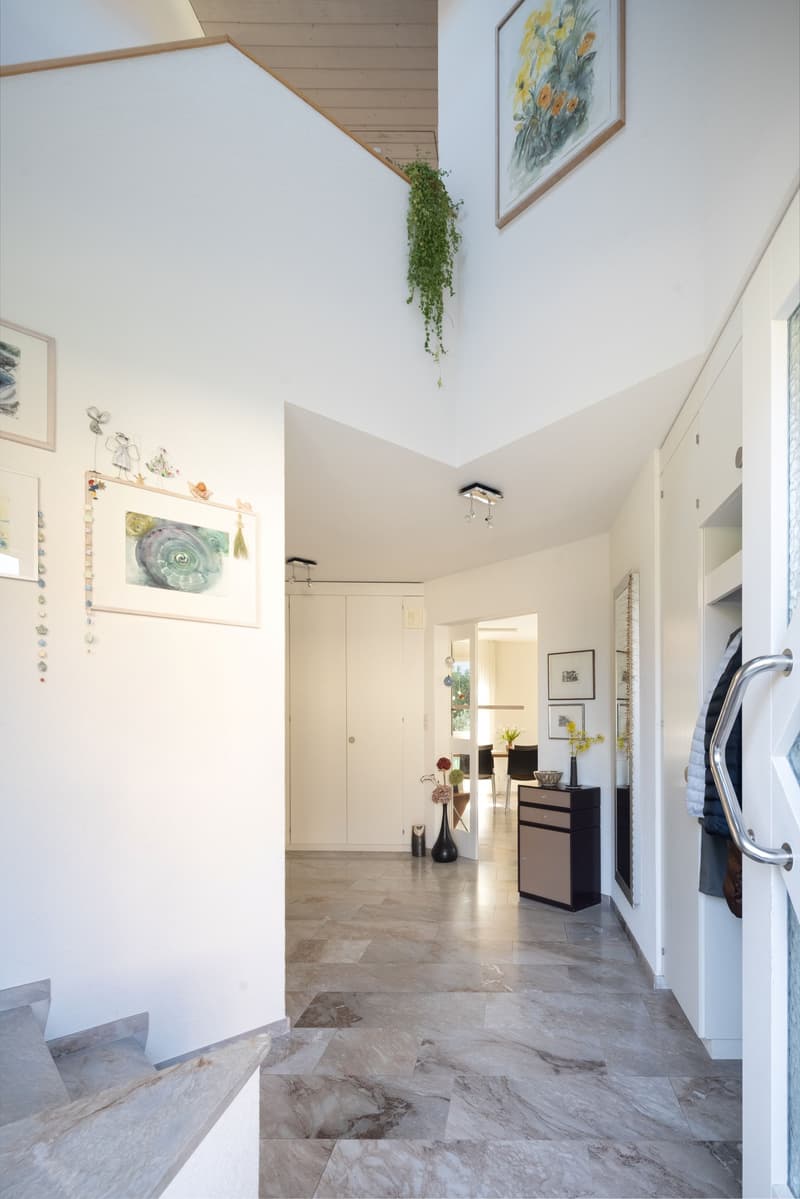 marble floor, white walls, decorative items, framed pictures, staircase, cabinet, mirror, table with flowers, chairs, and a desk