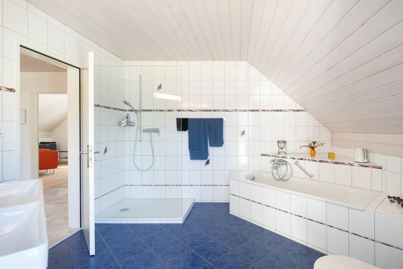 white tiled walls, blue tiled floor, shower, bathtub, sink, towel rack