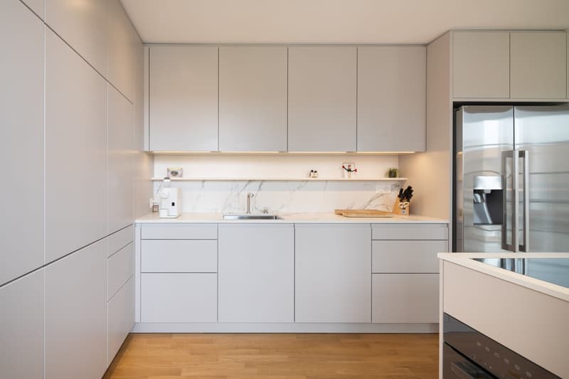 modern kitchen with white cabinets, marble countertop, stainless steel sink, refrigerator, wooden floor