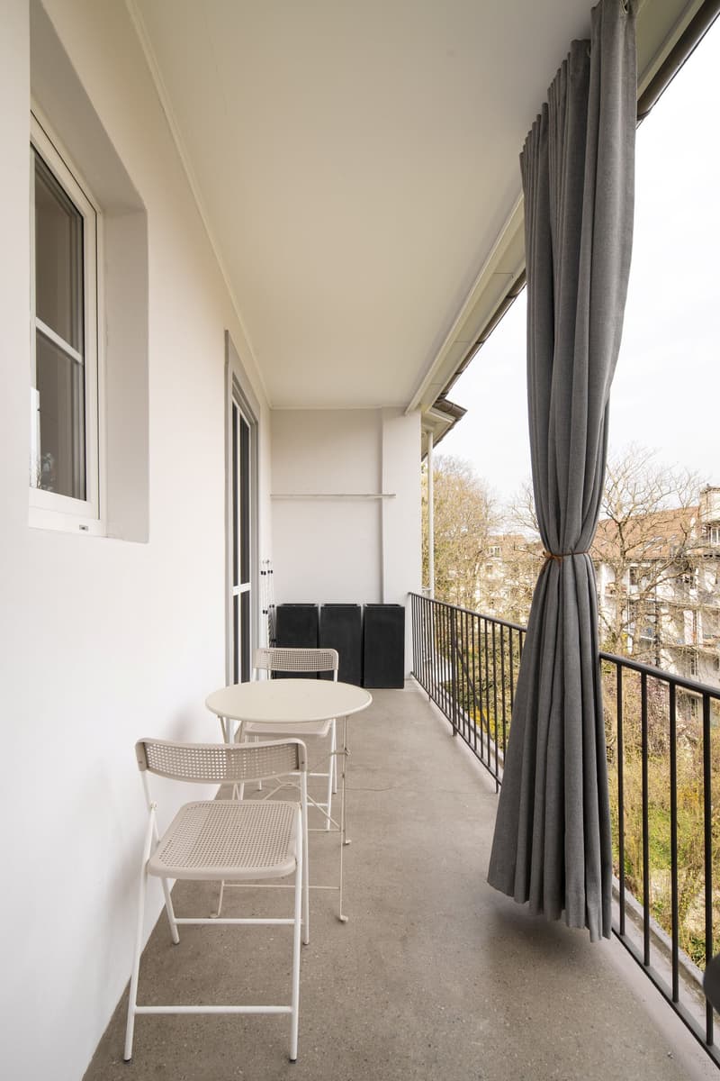 Balcony with white chairs, table, and gray curtains