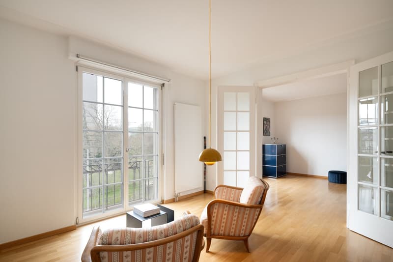 wooden floor, large windows, balcony, two armchairs, table, lamp, cabinet