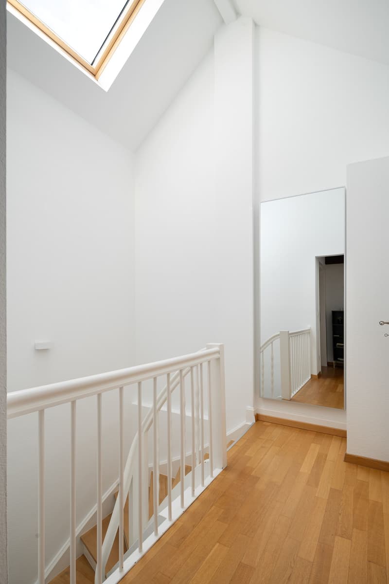 white walls, wooden floor, white railing, skylight, mirror