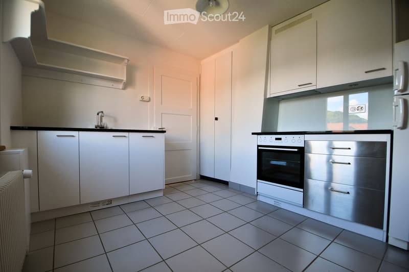 modern kitchen with white cabinetry, black countertops, silver appliance, stainless steel drawer, sink, faucet, oven