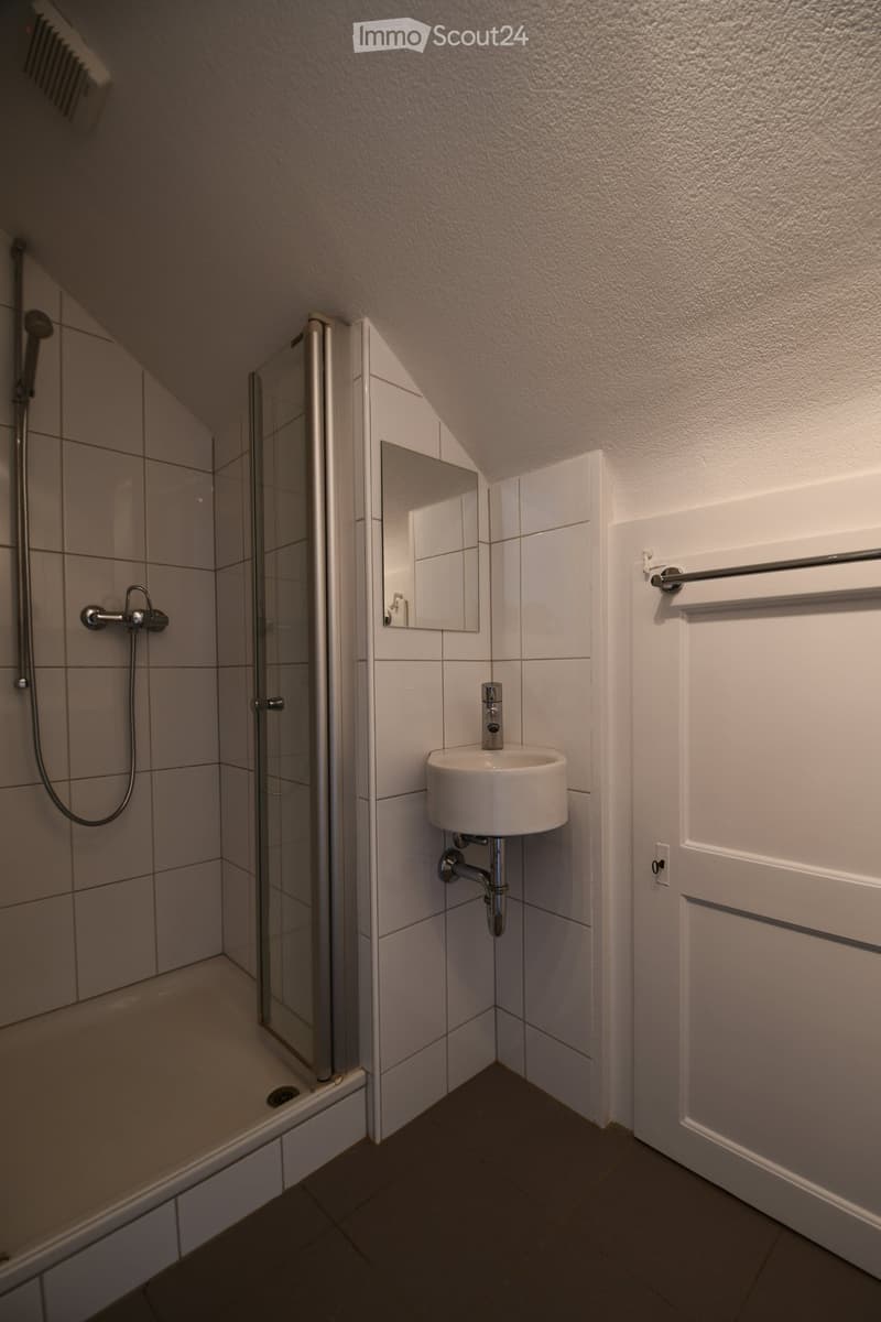 white tiled shower, white sink, mirror, towel rack