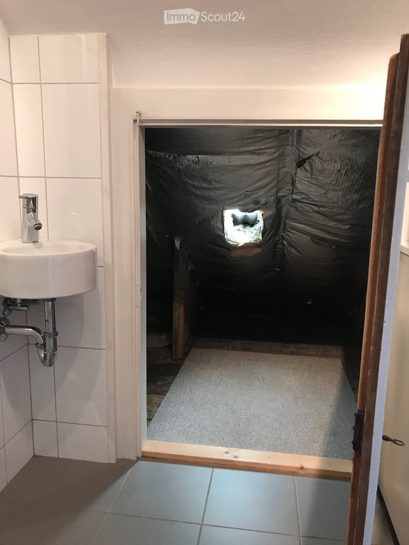 Small bathroom with grey floor, white tiles, sink, tiled walls