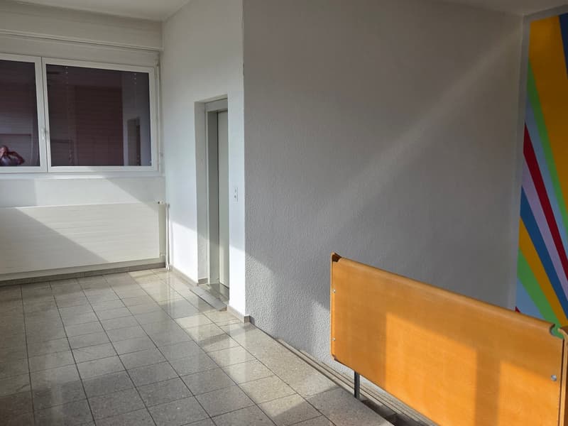 room, white walls, floor with tiles, window, radiator, colorful painting, empty