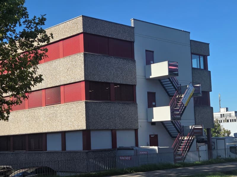Three story building, white and red panels, two emergency staircases