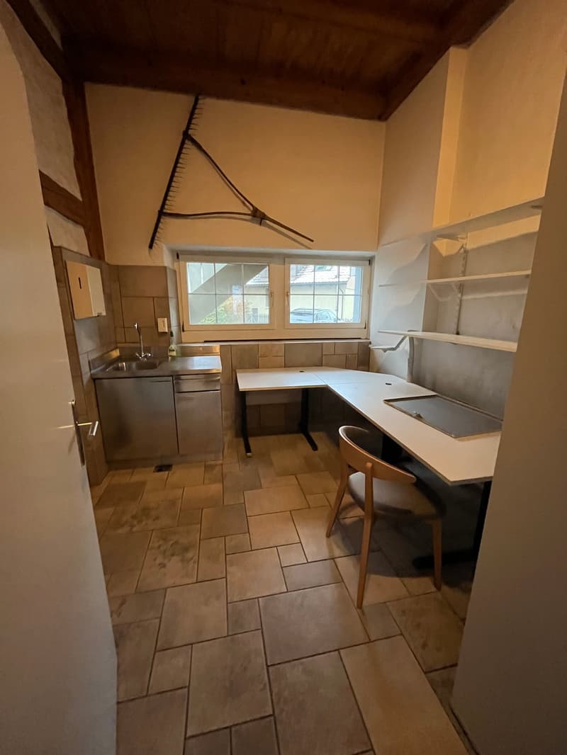 Small kitchen with tile flooring, wooden cabinets, stainless steel appliances, and a dining table with chairs