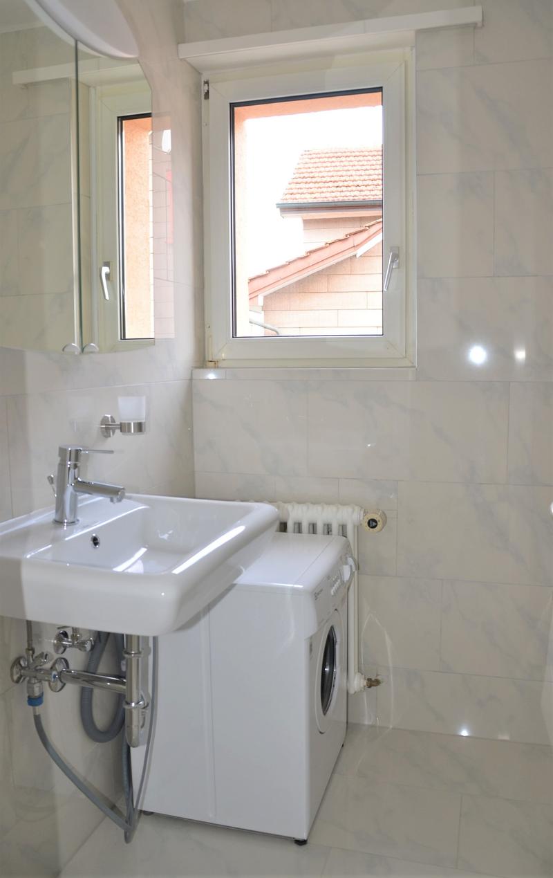 Bathroom with a white sink, mirror, washing machine, and radiator