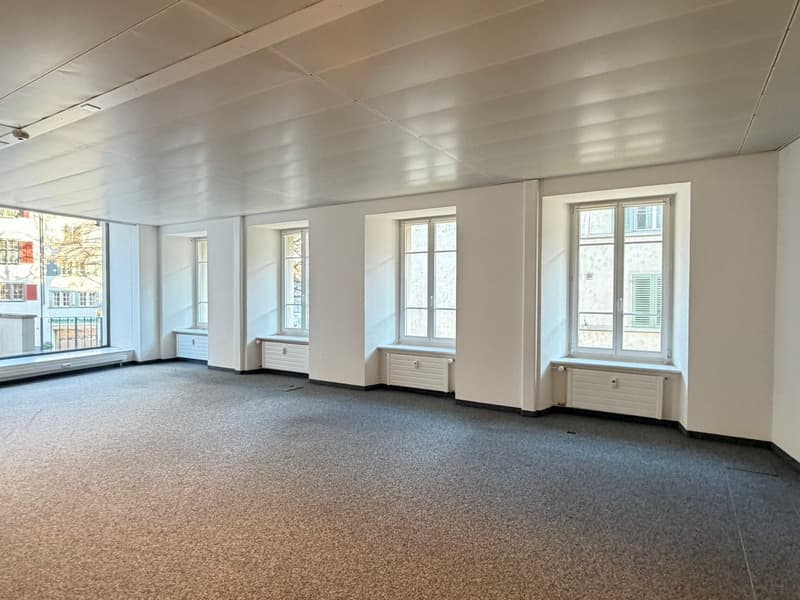 empty room, white walls, carpeted floor, three windows, white radiators