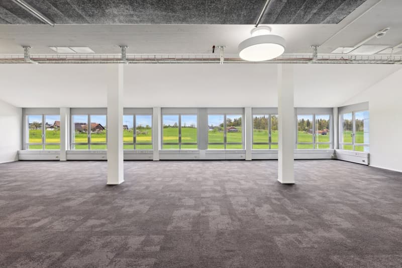 large open room, high ceilings, large windows, gray flooring, large view to the outside