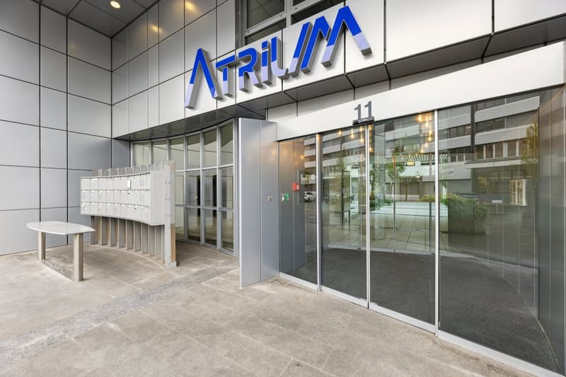 Atrium Building entrance with mail boxes, sliding entrance doors and a reception table.