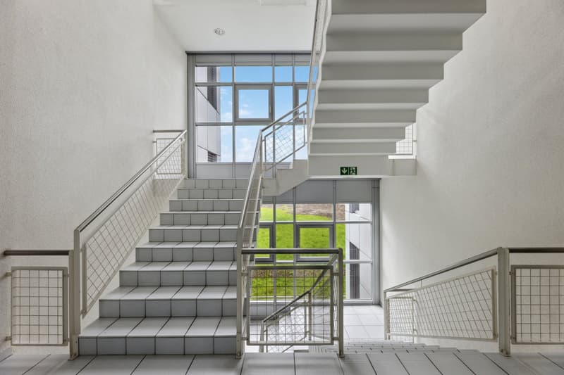 White tiled steps, metal railings, and glass panels with outside views.