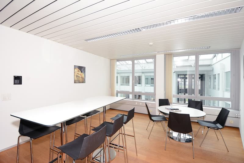 modern room with round tables, square tables, glass windows, wooden floor, white wall
