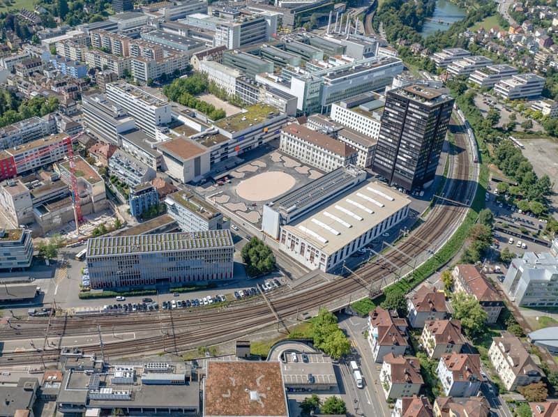 urban area with many buildings, large open area, central building with circular pattern on the ground
