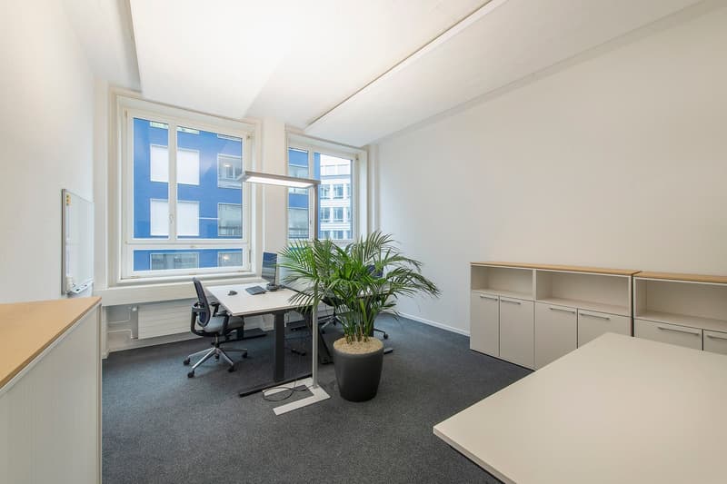 empty office with desk and office chairs, a white board, and plants
