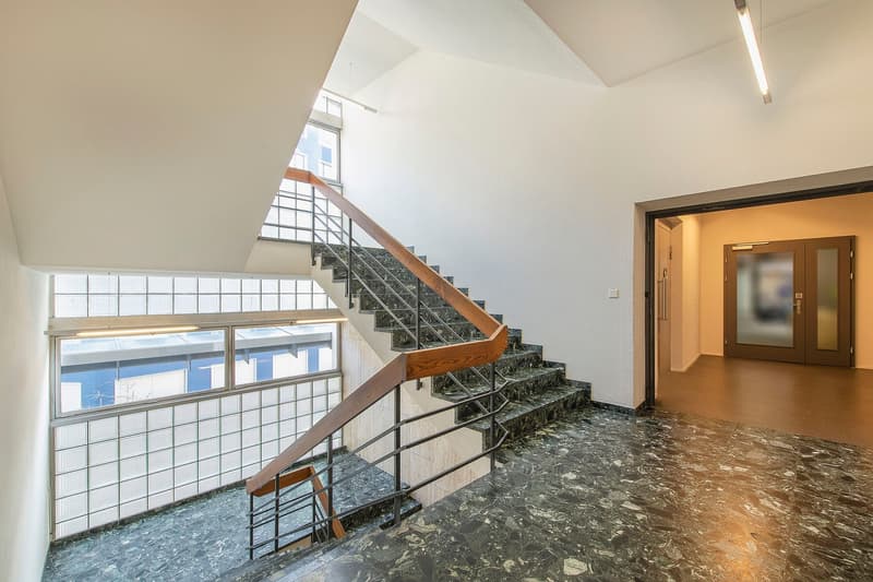 Wooden handrail, metal handrail, large window, tiled flooring, wooden staircase