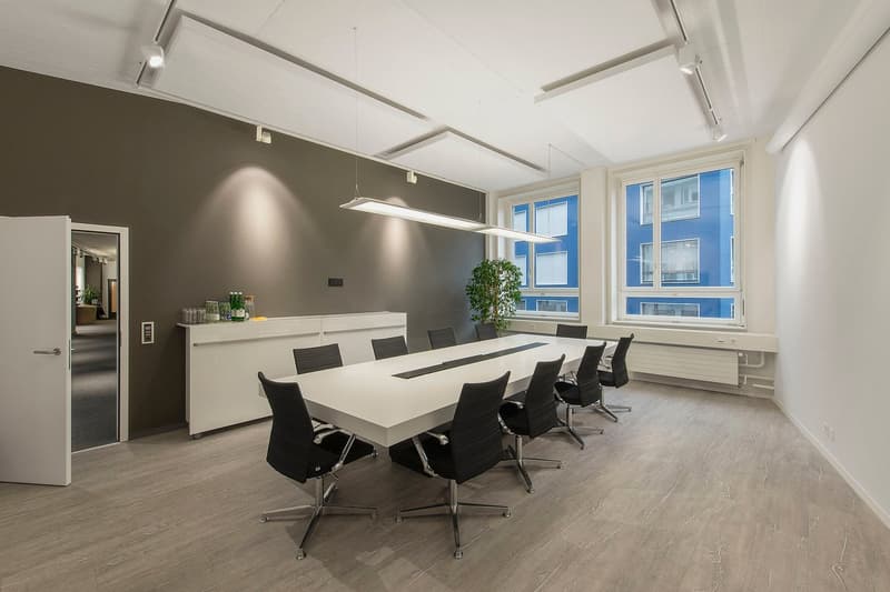 large rectangular table, black swivel chairs, white cabinets, lamps, windows