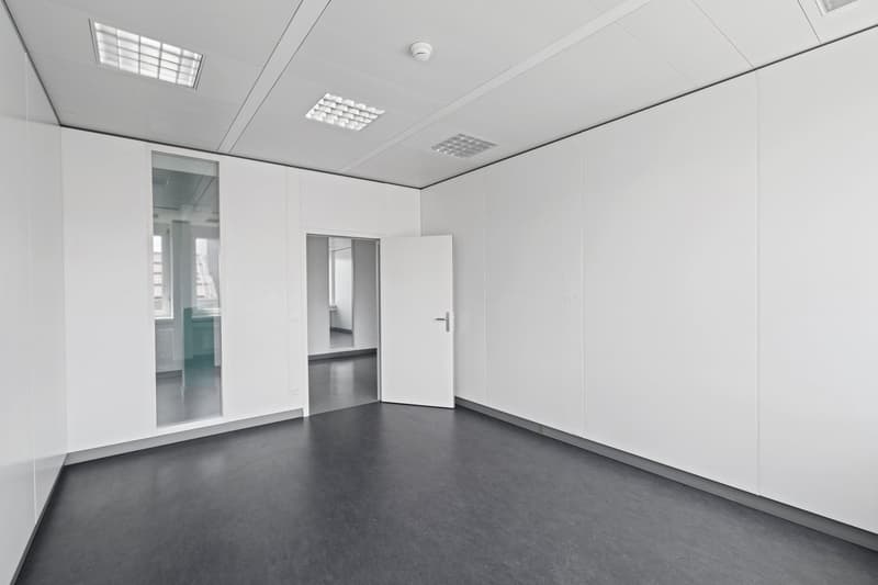 spacious room, high ceiling, grey floor, open door, white walls, security camera, glass panels
