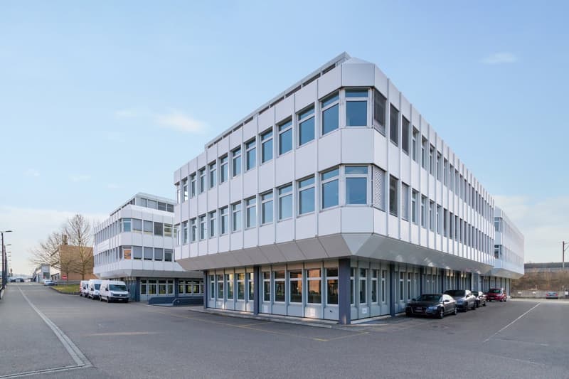 modern office building, white exterior, large windows, multiple floors, parking lot in front