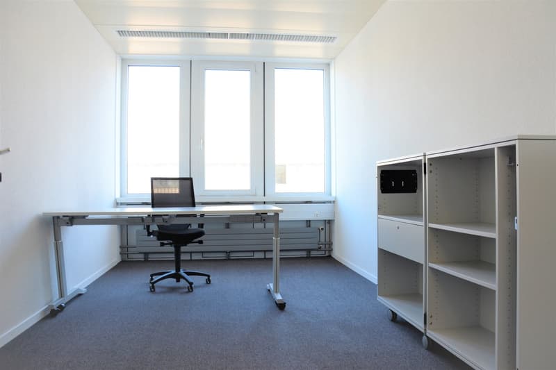 Modern office room with desk, chair, and shelves, large windows providing natural light