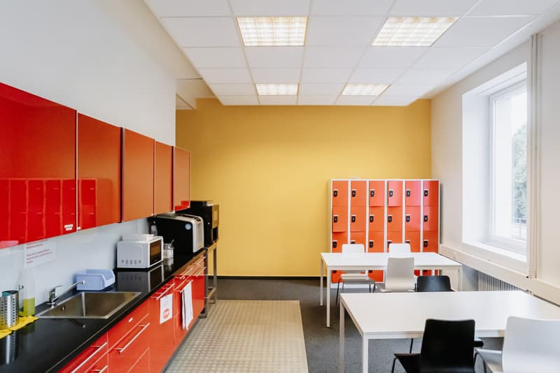 white ceiling, yellow wall, red cabinets, 2 microwaves, 2 tables, chairs, sink