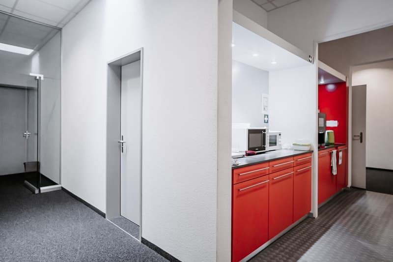 minimalistic kitchen with red cabinets, gray tiled floor, microwave, kitchen tools, white walls