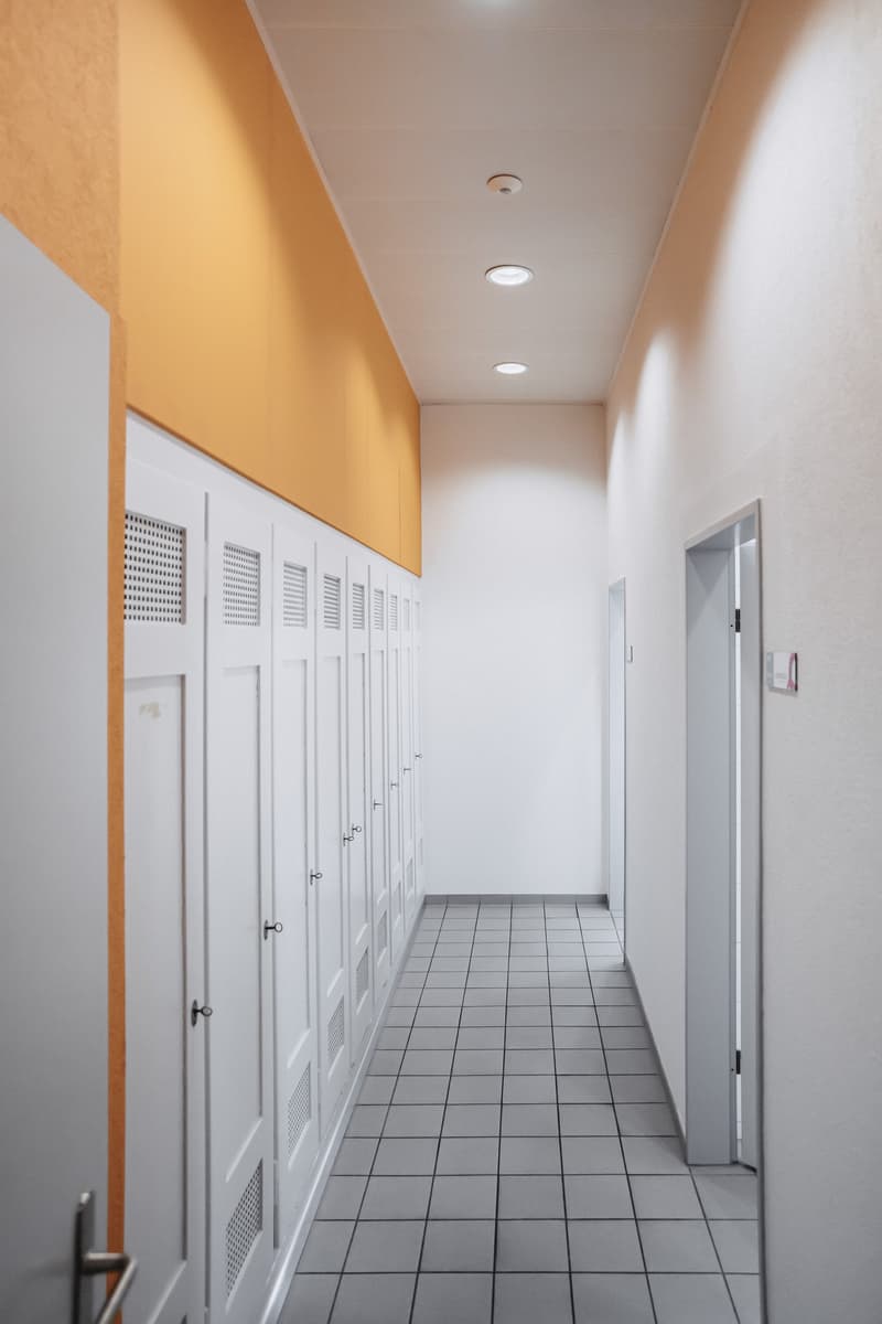 white tiled floor, white wall, long hall, lockers on one side