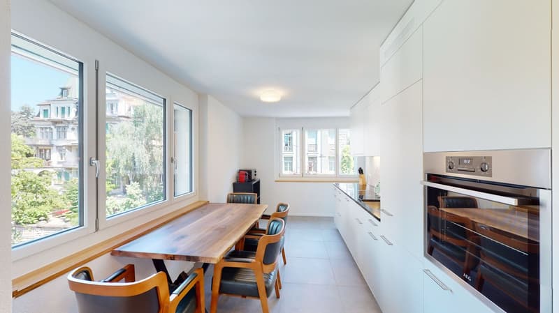 dining room, wooden dining table, chairs, modern white kitchen, oven, sink, large windows, kitchen island