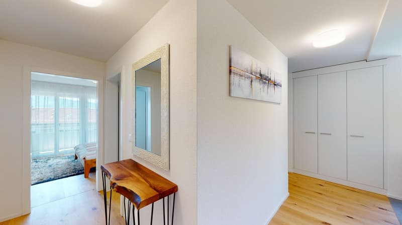 white walls, wooden floor, wooden side table, white mirror, large windows, artwork