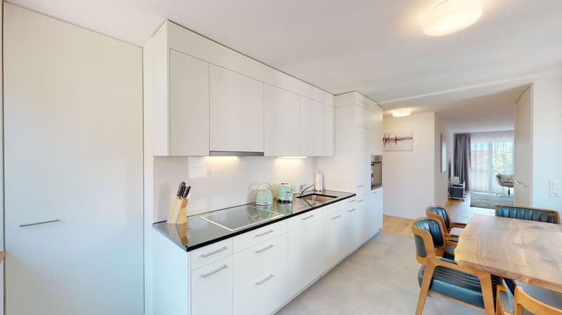 Modern kitchen with white cabinets, granite countertops, integrated appliances and an island with seating