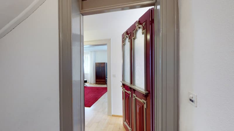 entryway with wooden floor, white walls, red door, and red carpet