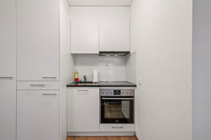 modern kitchen, white cabinets, wooden floors, black countertops, stainless steel oven and dishwasher, open shelving