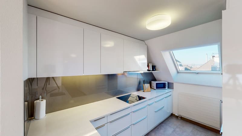 modern kitchen with white cabinets, silver and black appliances, induction hob, kitchen island, white counters, white porcelain floor, skylight window, microwave, knives, sink, tissue