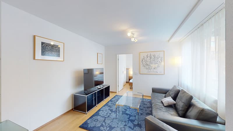 living room with TV, couch, coffee table, rug, artwork, open door to bedroom, sliding glass doors