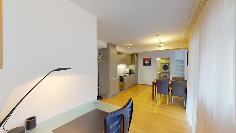 open floor plan, hardwood floors, white walls, desk, modern kitchen, dining table, washing machine, visible dining area