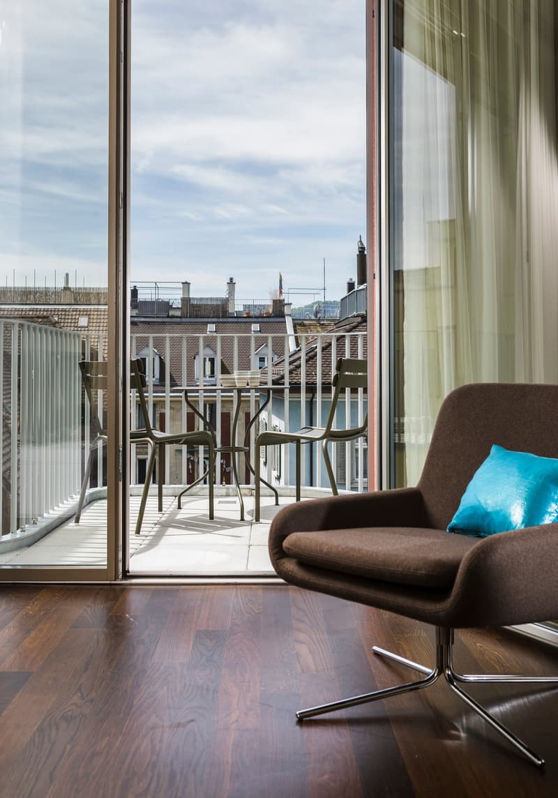large sliding doors, wooden floor, modern armchair, view of the balcony, table with 4 chairs, 4 bowls