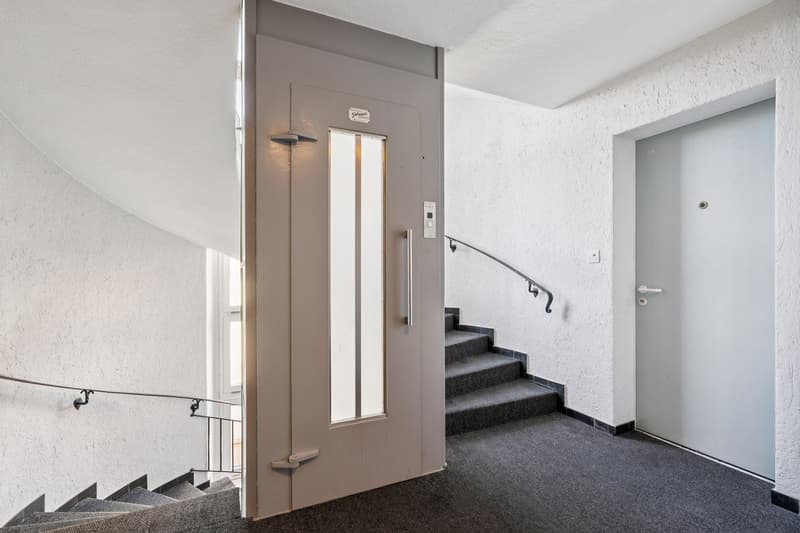 elevator, white walls, carpeted stairs, metal handrail, landing area