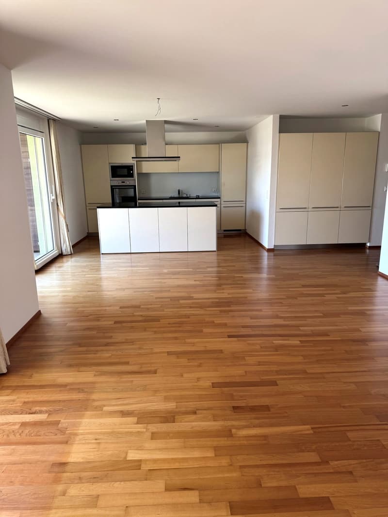 modern kitchen with white cabinets, wooden floor, island with black countertop, built-in oven and microwave, sink with faucet