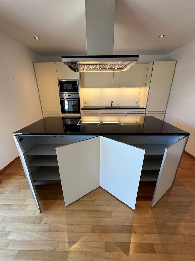 modern kitchen with island, black granite countertop, white cabinets, stainless steel appliances, wooden floor