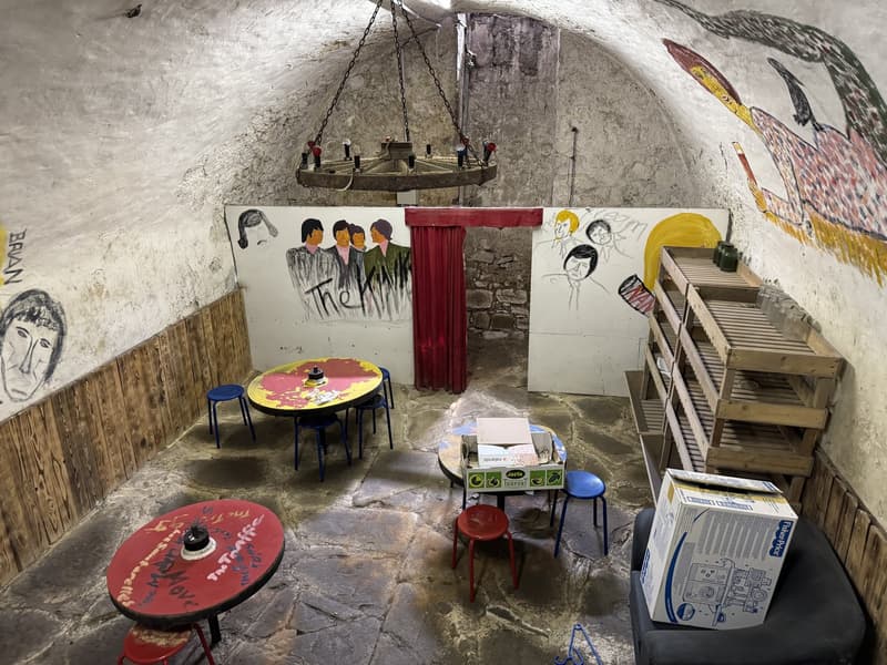 stone floor, hanging chain, graffiti, furniture, tables, wooden shelves
