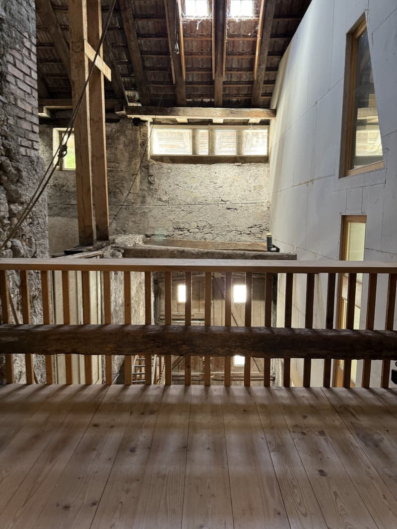 exposed wooden beams, stone walls, wooden floor, wooden balcony, windows