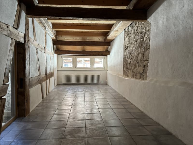 tiled floor, wooden beams, white walls, window with white frames, radiator, no furniture