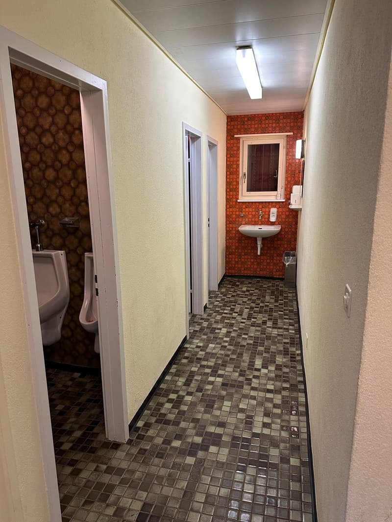 tiled flooring, two urinals, sink, trash bin