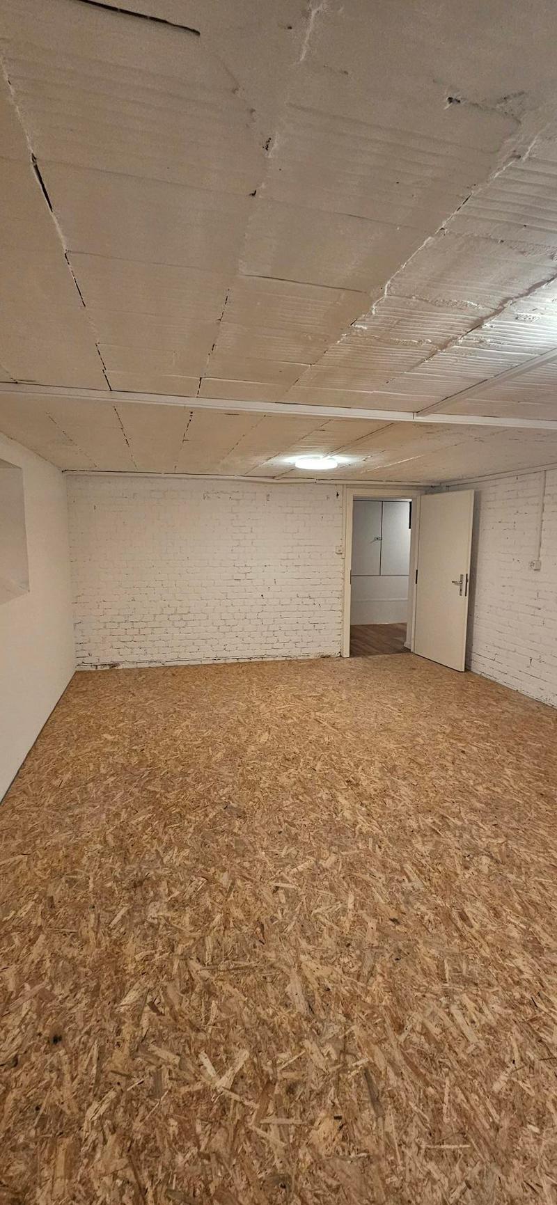 large room, brick walls, particleboard floor, white doors
