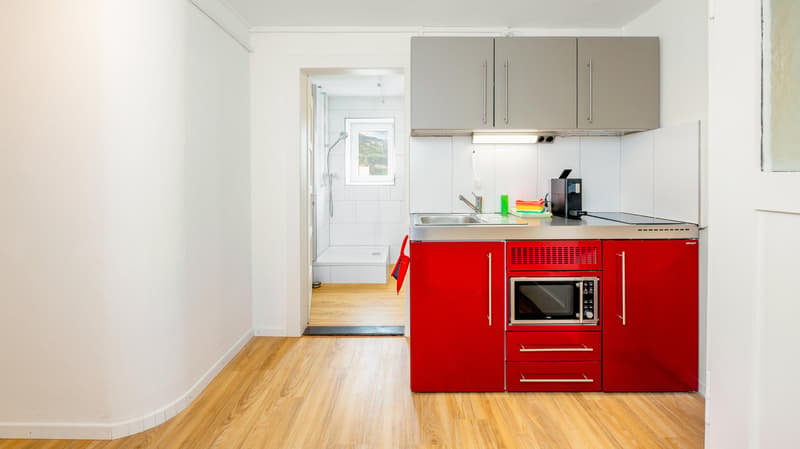 small open kitchen, silver appliances, white and grey cabinets, stainless steel countertop, red drawers
