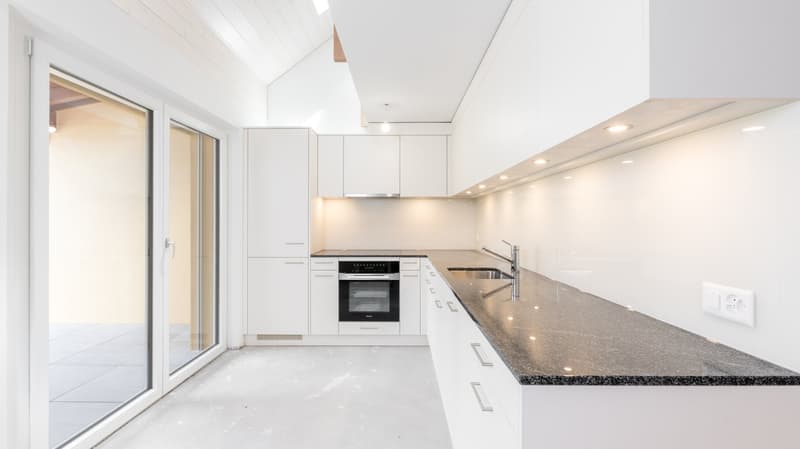 Spacious modern kitchen with white cabinets, granite countertops, built-in oven, and dishwasher. Large sliding glass door leading to an outdoor area.