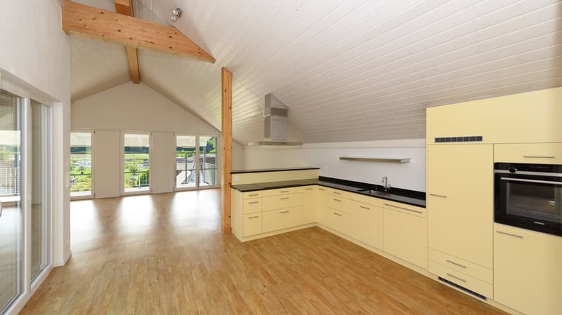 Offene und helle Küche mit Blick in den Wohnraum und den Balkon