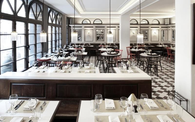 Chandeliers, wooden floors, arched windows, tables, chairs, checkered flooring, and a marble counter