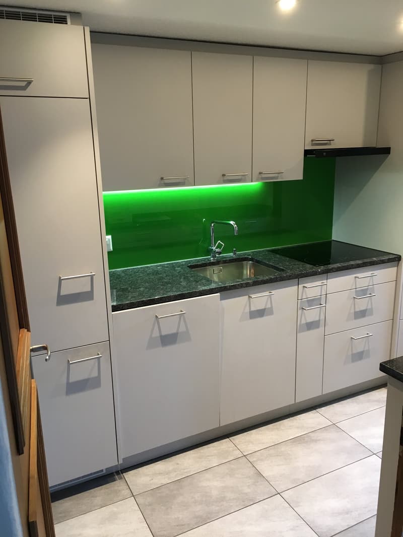 modern kitchen, white cabinets, green backsplash, granite countertop, stainless steel sink, faucet, black stovetop